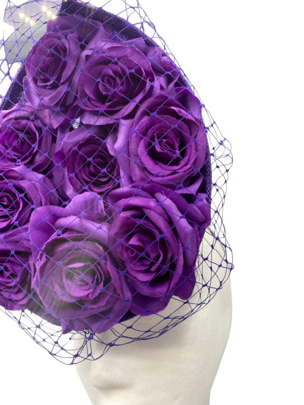 Cadbury purple coloured percher hat with purple roses in the centre and finished with a purple netting over the headpiece.